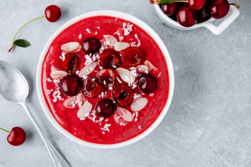 Red cherry smoothie with fresh berries, almond flakes and coconut chips.
