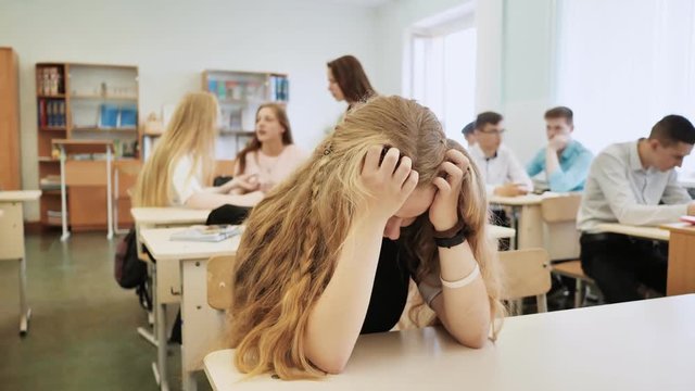 The girl is a schoolgirl crying in class and her classmates console her.