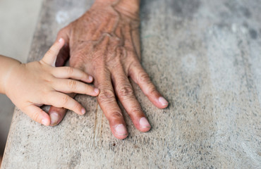 The hand of the little boy are touching the elderly hand, wrinkl