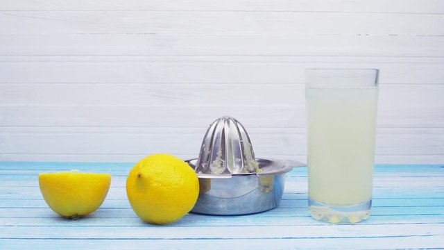 Freshly Squeezed Bio Organic Lemons With Stainless Steel Juicer And Glass Full Of Lemonade With Ice Cubes On Blue Wood Board Slide Down Movement Summer Concept