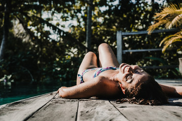 .Young and pretty woman enjoying her vacation in Ubud, in the Bali island, Indonesia. A summer afternoon in the pool with a tropical background. Relaxed and happy attitude. Lifestyle.