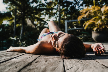 .Young and pretty woman enjoying her vacation in Ubud, in the Bali island, Indonesia. A summer afternoon in the pool with a tropical background. Relaxed and happy attitude. Lifestyle.