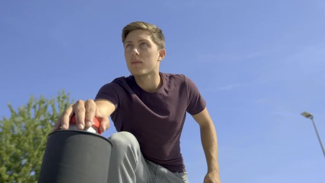 Low potrait shot of a  Freerunner who presses red game show buzzer and looking into the distance. 