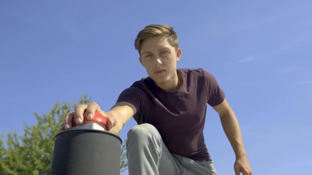 Filmed from down below: charismatic young freerunner who presses red game show buzzer, then looks ups into the camera 
