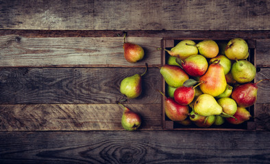 fresh pears with leaves in a wooden box on wooden background