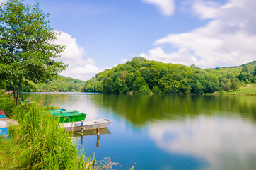 Wooden pier or jetty and a boat on lake sunset and sky reflection water.