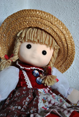 Pretty doll with a straw hat sitting there and „looking“ at the camera