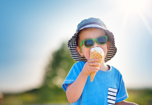 Happy child eating ice cream outdoors in summer