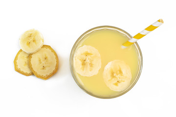 Glass of banana smoothie on white wooden background from top view
