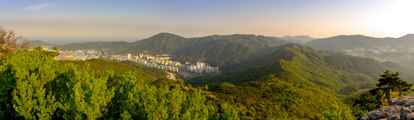 Obraz premium Panoramic top view of Guksabong mountain. View from its peak, It has mountain ridge with city and shipyard on the leftside.Fog sky in the evening.