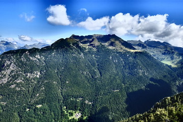 Naklejka na ściany i meble Profilo di una cima delle Alpi Italiane sovrastata da nuvole che spiccano su un cielo azzurro. 