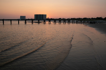 Obraz premium Old wooden pier and ocean in foreground at sunset