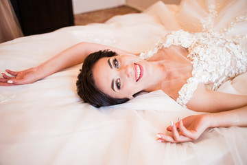 The bride in the white dress is lying on the bed