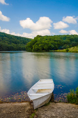 Wooden pier or jetty and a boat on lake sunset and sky reflection water.