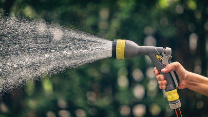 Hand hält Gartenschlauch mit Wasserspritze