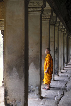 Buddhist monk in a colonnaded corridor in a temple in Angkor Wat, Siem Reap, Cambodia