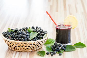 Fresh juice of chokeberry or Aronia melanocarpa in glass and berry in pot on wooden background