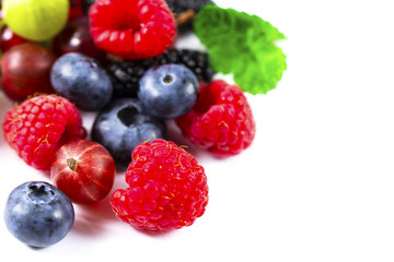 Close-up arrangement mixed, assorted berries including blackberries, strawberry, blueberry, raspberries and fresh leaf on white