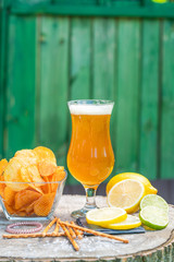 A glass of cold beer on wooden stump in the garden