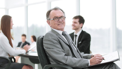 pensive mature businessman in suit with his team working behind