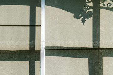 beschattetes Fenster mit Schatten von Verzierung auf dem Rollo