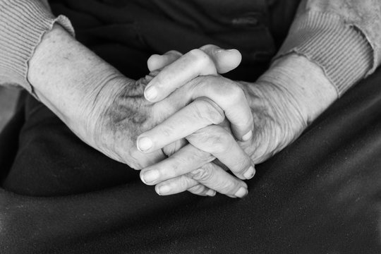 Hands of an old woman on her lap - black and white, selective focus