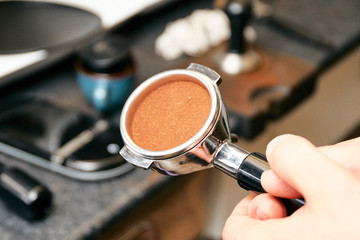 Close-up shot of barista espresso machine portafilter, filled with coffee