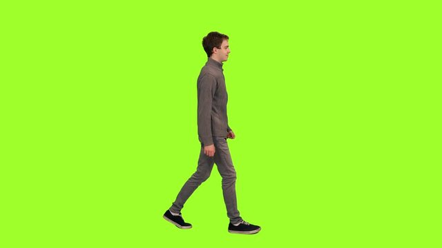 Young handsome caucasian man in casual wear walking on green chroma key background