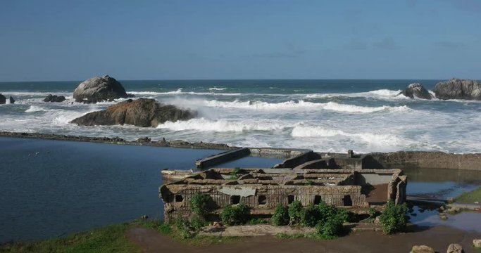 Heavy surf beyond the breakwater at Sutro Baths in San Francisco. Bright sunny morning, blue sky.
