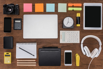 top view of arranged workplace with smartphones, laptop, digital tablet, photo camera and stationery