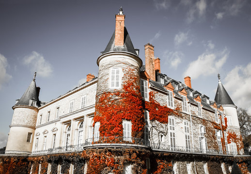 Rambouillet castle overgrown with red grape leaves in autumn. Rambouillet, France. Retro toned vintage postcard style photo.