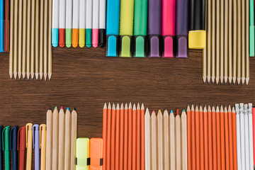 flat lay with arranged colorful pencils and markers on wooden table