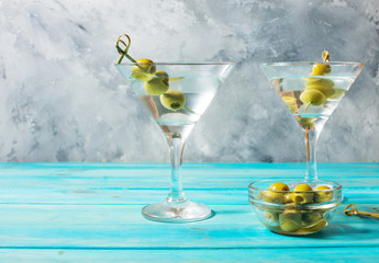 Martini cocktail with green olives on blue wood background