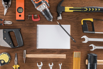 top view of empty textbook surrounded by arranged various tools on wooden table