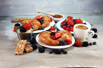Delicious breakfast with fresh croissants and ripe berries on old marble background.