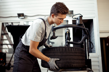 A handsome mechanic is helping his workmates at a car service