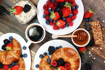 Delicious breakfast with fresh croissants and ripe berries on old marble background.