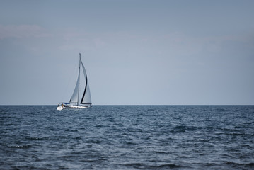 White yacht with sails in the open sea.