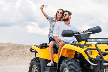 attractive young couple taking selfie while sitting on ATV in desert © LIGHTFIELD STUDIOS