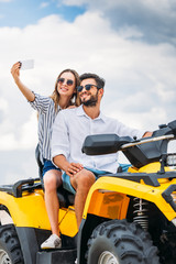Fototapeta na wymiar smiling young couple taking selfie while sitting on ATV