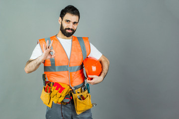 Man Builder with beard standing on gray background, copy space.