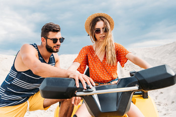 Fototapeta premium handsome young man teaching his girlfriend how to ride atv in desert