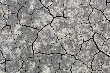 Close-up cracked black earth soil due to hot sumer without rain. Arid season, agrucultural disaster. Global warming up process aftermath