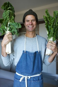Man in apron smiling holding spinach