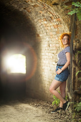 Young woman with ginger hair standing near tunel entrance outdoors