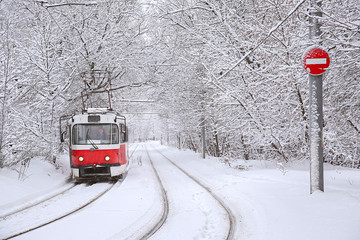 red tram rides on a snow-covered alley in the city