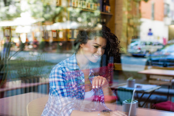 beautiful smiling woman  sitting by the window. view from outside.