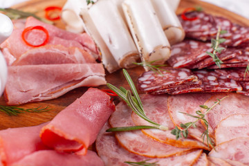 Food tray with delicious salami, pieces of sliced ham, sausage. Cutting sausage and cured meat on a celebratory table.