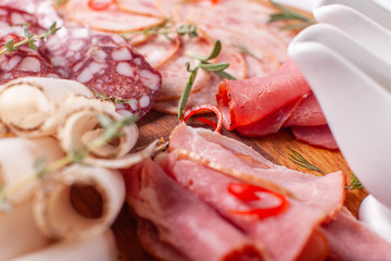 Food tray with delicious salami, pieces of sliced ham, sausage. Cutting sausage and cured meat on a celebratory table.