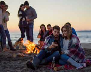 Couple enjoying bonfire with friends on beach